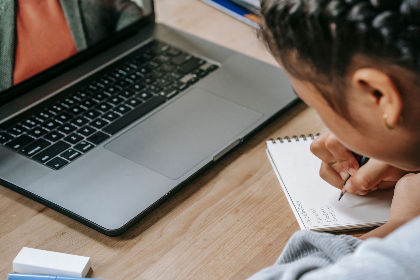 A student learning online, watching a lesson and taking notes